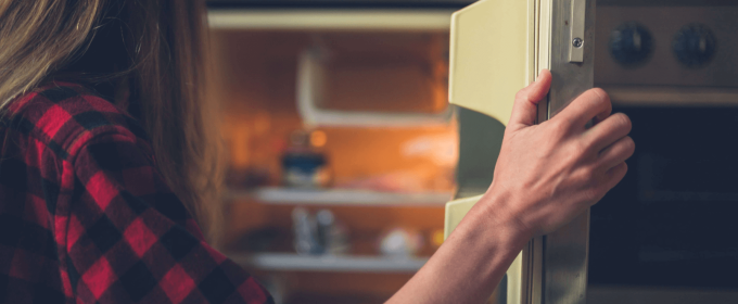 a woman opening a refrigerator door in a kitchen