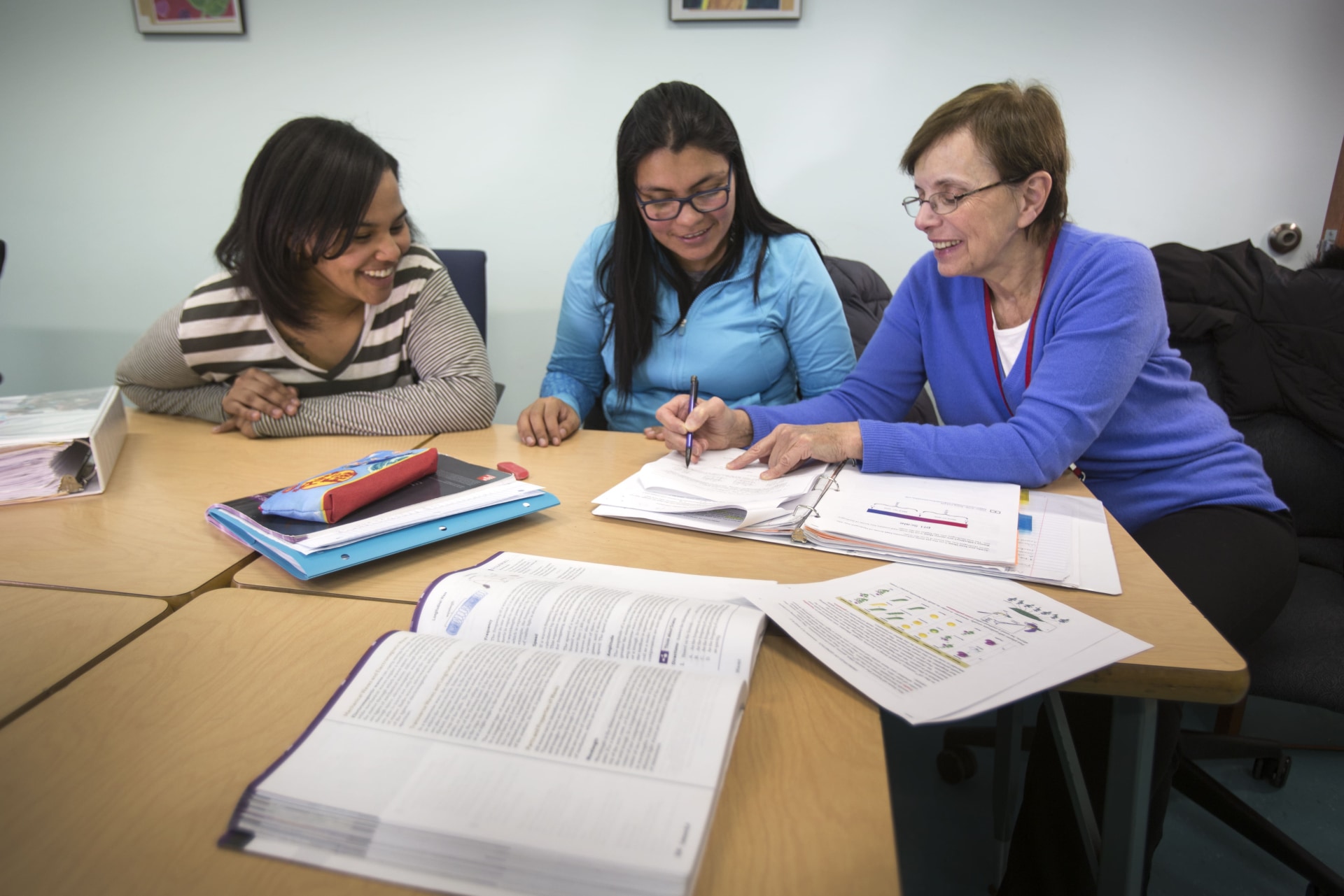 a group of women sitting at a table with books