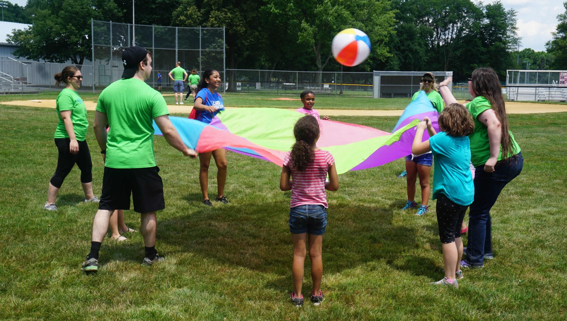 a group of people playing with a colorful fabric