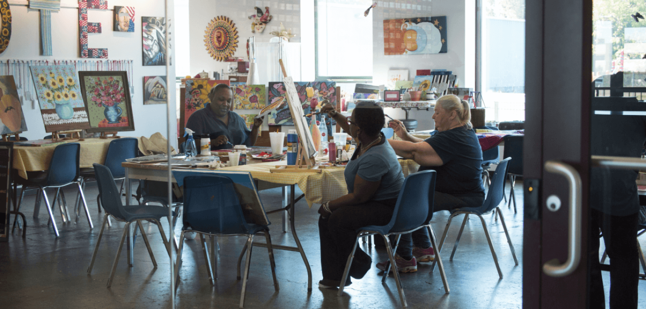 a group of people sitting at a table painting